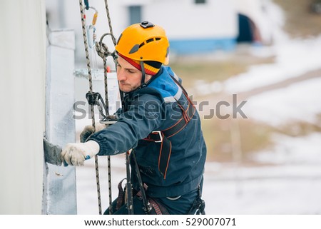 Professional industrial climber in orange helmet works at height. Risky extreme job.  Royalty-Free Stock Photo #529007071
