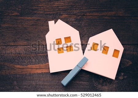 Two lodges from white paper on a wooden background. Symbol of the house, family, cosiness. Concept image house. Concept of sale or purchase house