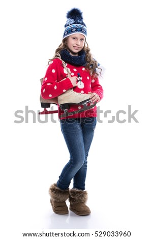 Pretty smiling little girl with curly hairstyle wearing knitted sweater, scarf and hat with skates isolated on white background. Winter clothes and sport concept.