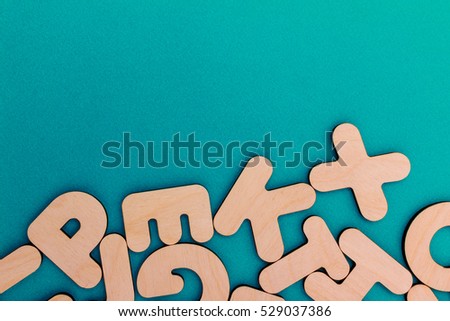 English alphabet made of natural yellow wood randomly scattered on a blue background. Latin letters.