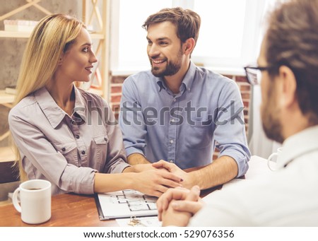 Beautiful couple is talking with handsome realtor in suit and smiling