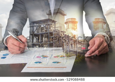 Double exposure of businessman working with document, calculator for analyze in the work, electric Generating Factory, Power Reactor and sunset as industrial, energy, analysis and commitment concept. Royalty-Free Stock Photo #529088488