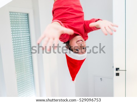 Funny boy hanging down at home with Santa hat