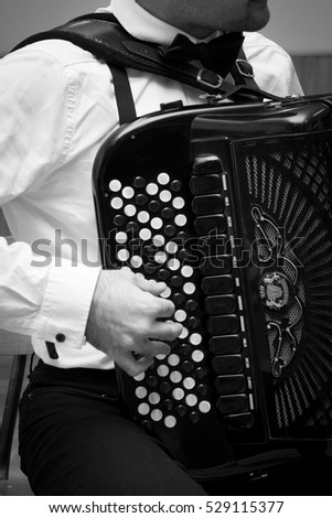 Man hand playing accordion with round button,black and white