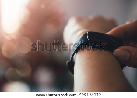 Woman using smart watch with a christmas tree in the background Royalty-Free Stock Photo #529126072