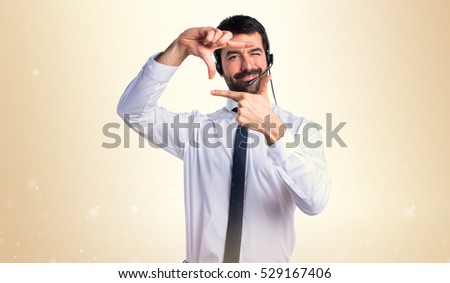 Young man with a headset focusing with his fingers on ocher background