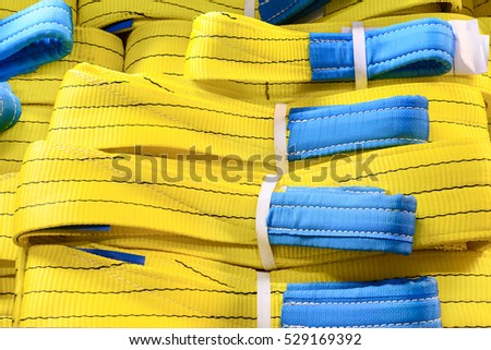 Yellow nylon soft lifting slings stacked in piles. Warehouse of finished products for industrial enterprises