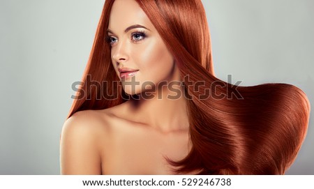 Beautiful model girl with shiny red  straight long  hair . Care and hair products .