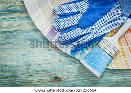 Composition of protective gloves color sampler paintbrushes on wooden board construction concept.