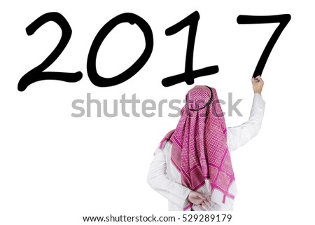 Back view of middle eastern male entrepreneur is writing numbers 2017 on the whiteboard