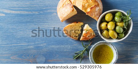 Olivier oil with fresh herbs and bread. Blue background. Italian and Greek national food