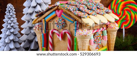 Festive Christmas Gingerbread House decorated with candy canes, marshmallow cones, chocolates and candy, sized to fit a popular social media cover image placeholder.