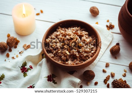 Christmas porridge with candles on white wooden background