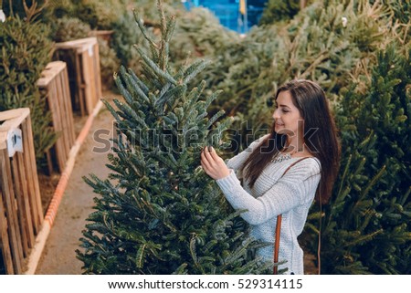 beautiful girl chooses a Christmas tree at the fair