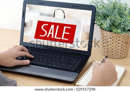 Hand typing labtop with sale over shopping bag background on screen, digital marketing, online shopping, business, E-commerce
