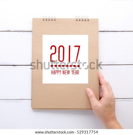 Hand holding recycle paper notebook with Happy new year 2017 on cover background, new year concept

