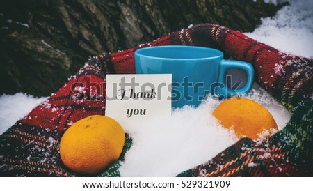 Cup of tea, red scarf and tangerines, words on paper thank you