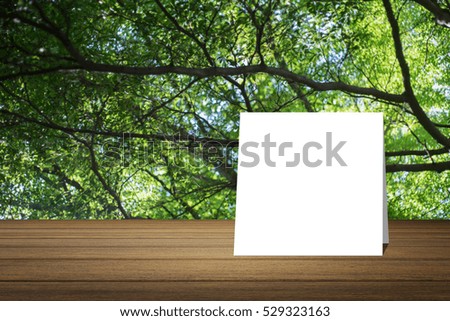 White card put on wooden desk or wooden floor on blurred green tree nature background.use for present or mock up your product.product display template.Business presentation.clipping path include