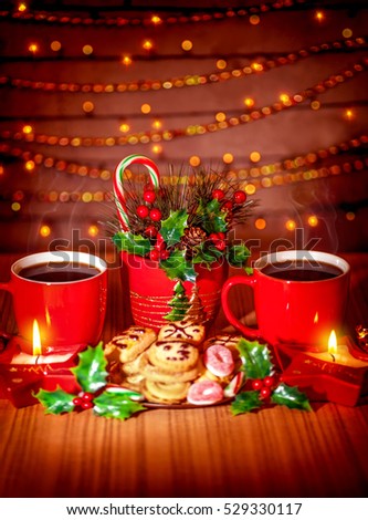 Christmas sweets still life, tasty hot coffee and homemade gingerbread decorated with holy berry and candles over glowing garland background