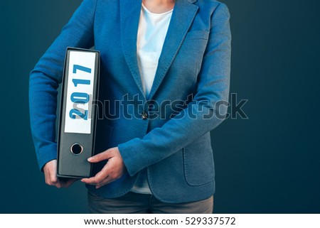 Businesswoman holding 2017 document binder with archived files for the past business year