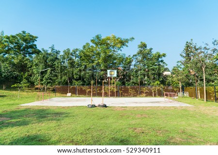 Basketball hoop in the park with green trees in background
