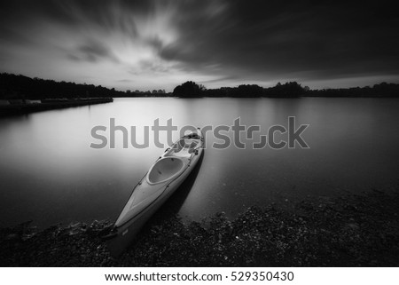 Dreamy boat parked at lake during sunset. Long exposure black and white photography.