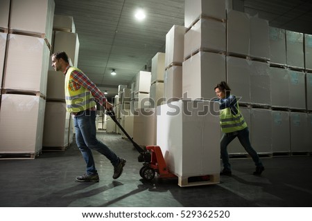 Man and a woman working with small forklift in a warehouse. First in first out, last in last out, just in time concept photo.