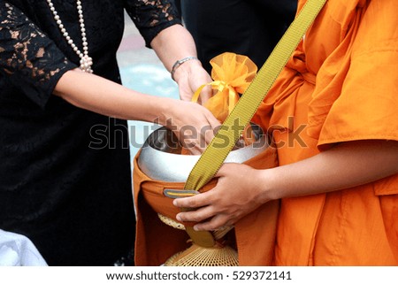 Monk receive food from black dress women, offer food to monk.
