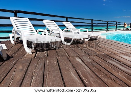 Luxury sunbeds on wooden floor near swimming pool, outdoor near caribbean sea
 Royalty-Free Stock Photo #529392052