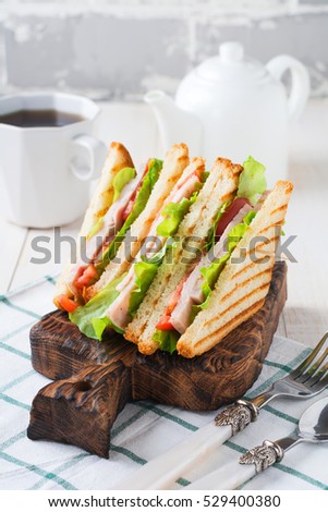 Sandwich for breakfast with stuffed tomatoes with ham and lettuce on a light wooden background. Selective focus.