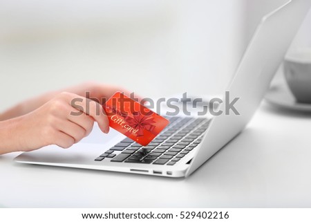 Woman with gift card and laptop, closeup. Shopping online. Holiday celebration concept.