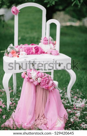 dressing table and white chair with floral decoration standing outdoors