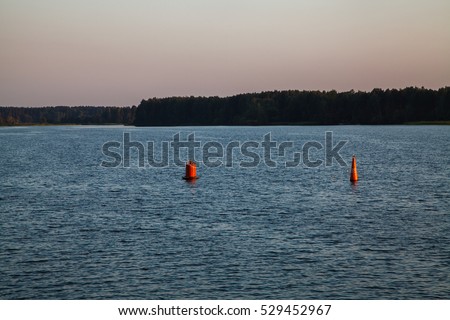 Two red buoys in the blue river. Sunset.