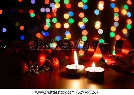 Burning candle on a table with Christmas decorations on a background garlands