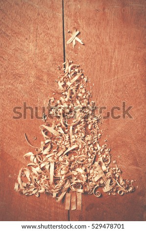 Simple Christmas tree arranged from sawdust, wood-chips on wooden background. 