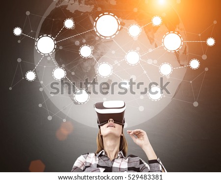 Woman in virtual reality glasses is standing in a black room. There is a planet and a network sketch above her. Toned image. Double exposure. Elements of this image furnished by NASA
