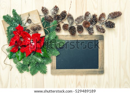 Pine branches with red flowers poinsettia and blackboard on wooden background. Christmas decoration. Vintage style toned picture
