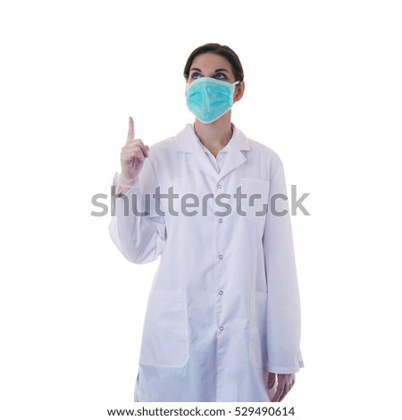 Female doctor in white coat over white isolated background in surgical mask pointing up, healthcare, profession and medicine concept