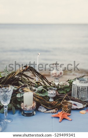 Wedding decoration. A table with a blue tablecloth decorated with flowers and shells on the beach. Close-up.