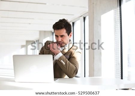 Young businessman using laptop at desk in new office