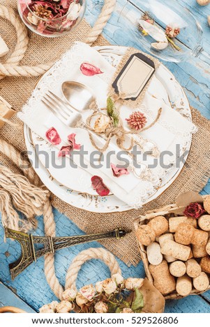 Tableware and silverware with dry flowers and different decorations on the blue old wooden background