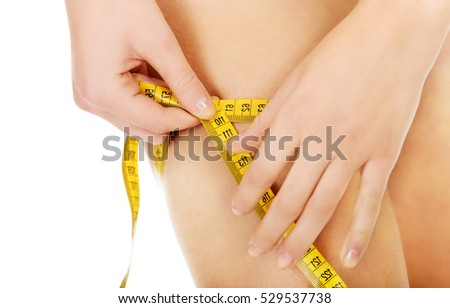 Young woman measuring her thigh