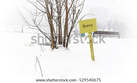 Yellow nameplate in the snow, the words on the plate sorry