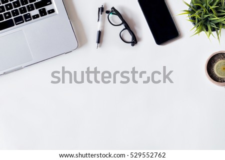 White office desk table with laptop, cactus, smartphone, pen, cactus, plant, and glass. Top view with copy space, flat lay.