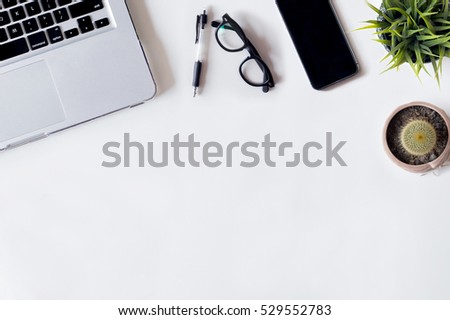 White office desk table with laptop, cactus, smartphone, pen, cactus, plant, and glass. Top view with copy space, flat lay.
