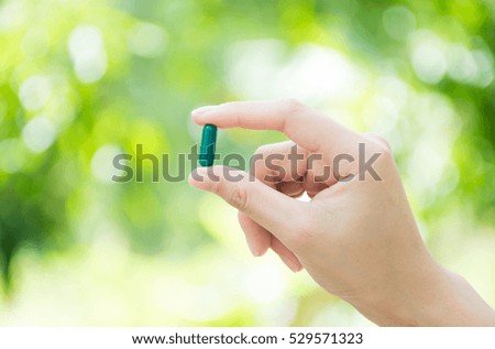 Medicine herb. Herbal pills with healthy medical plant on hand and natural background.