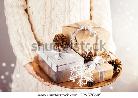 Young woman holding wooden tray with Christmas gifts. Holidays, new year or xmas concept. Toned image. Selective focus