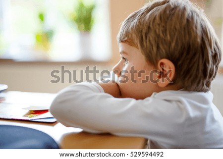Happy adorable preschool kid boy watching television while lying. Funny blond child enjoying cartoons on tv or computer