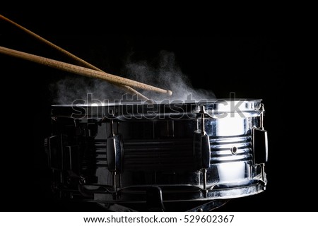 Drum sticks hit on the snare drum in black background, close-up, low key
