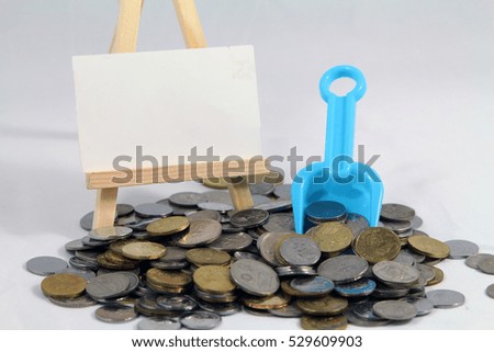 A financial conceptual image of a A Malaysia ringgit coins with a blue shovel toys. isolated white background with a blank white canvas frame on a wooden tripod stand